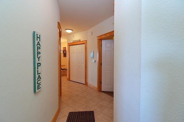 hallway featuring baseboards and light tile patterned flooring