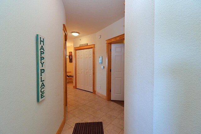 hallway featuring baseboards and light tile patterned flooring