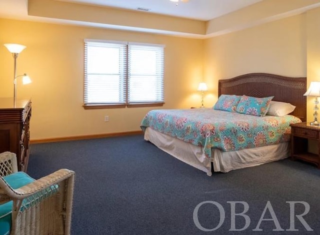 carpeted bedroom with a tray ceiling and baseboards