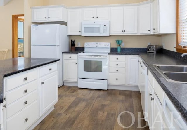 kitchen with white appliances, dark countertops, a sink, and white cabinetry