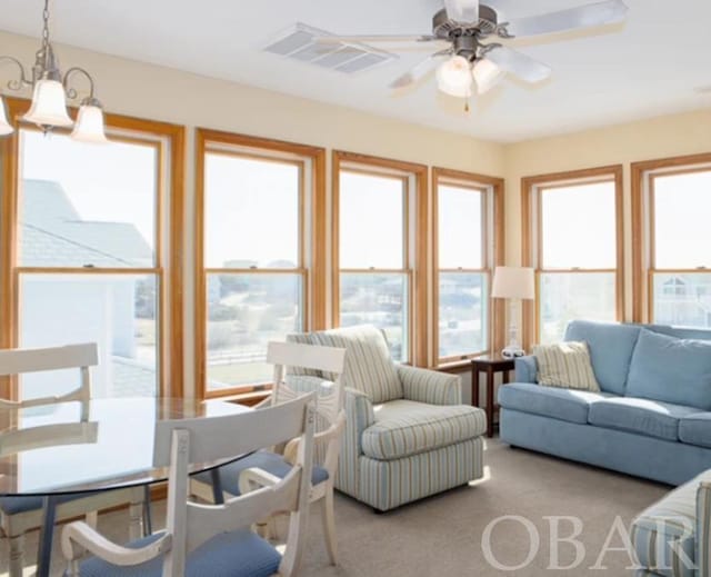 sunroom featuring visible vents, a wealth of natural light, and ceiling fan with notable chandelier