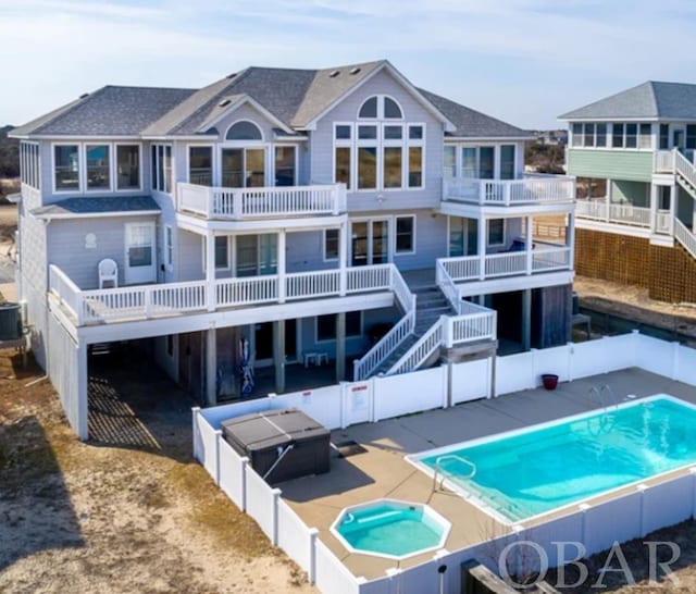 rear view of house with a fenced in pool, a fenced backyard, a residential view, an in ground hot tub, and central AC