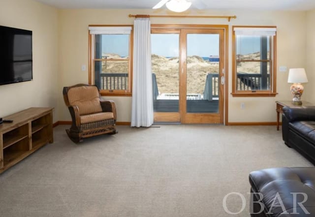 living area featuring light carpet and baseboards