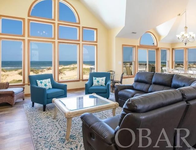 living area featuring high vaulted ceiling, a water view, wood finished floors, and an inviting chandelier