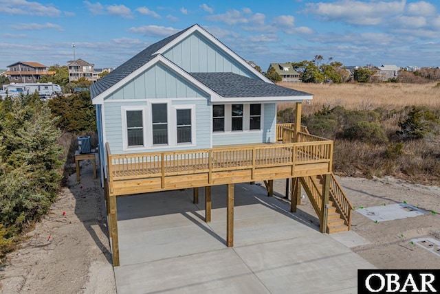 view of front of property with board and batten siding, a shingled roof, concrete driveway, cooling unit, and a carport