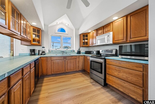 kitchen with glass insert cabinets, light countertops, white microwave, and stainless steel electric stove