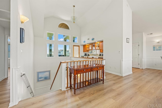 interior space with light wood finished floors, visible vents, and high vaulted ceiling