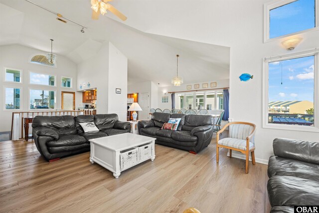 living area featuring high vaulted ceiling, light wood-type flooring, baseboards, and a ceiling fan