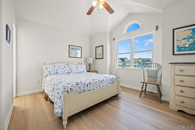 bedroom featuring light wood finished floors, ceiling fan, baseboards, and vaulted ceiling