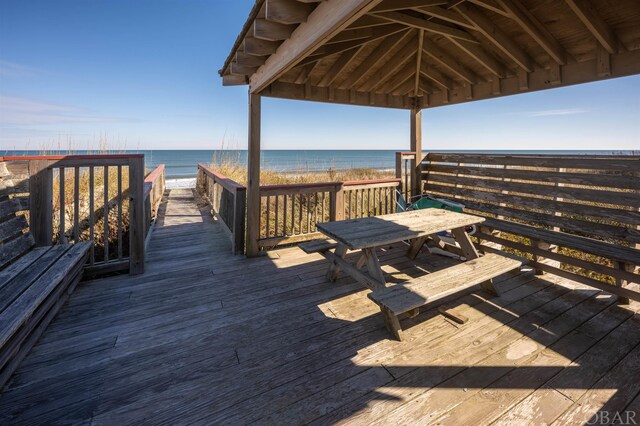 exterior space with a gazebo, outdoor dining space, a water view, and a view of the beach