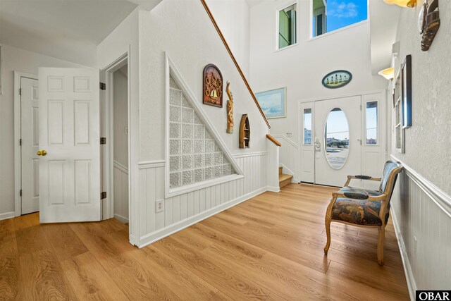 entrance foyer featuring light wood-type flooring, stairs, and wainscoting