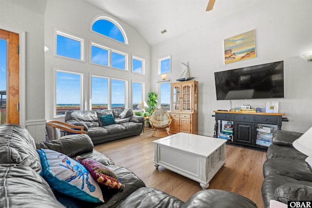 living area featuring visible vents, high vaulted ceiling, ceiling fan, and wood finished floors