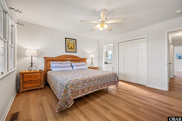 bedroom featuring visible vents, baseboards, a ceiling fan, light wood-style floors, and a closet