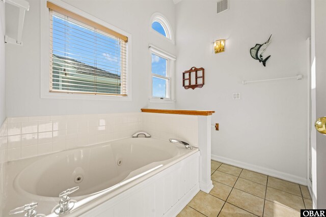 bathroom with baseboards, a tub with jets, visible vents, and tile patterned floors