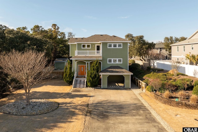 view of front of property featuring driveway, fence, and a balcony