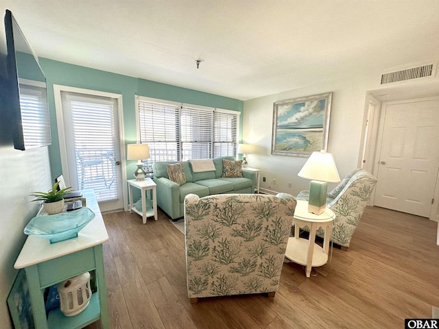 living area featuring visible vents and wood finished floors