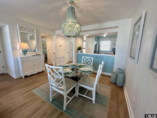 dining area with a chandelier, wood finished floors, and baseboards