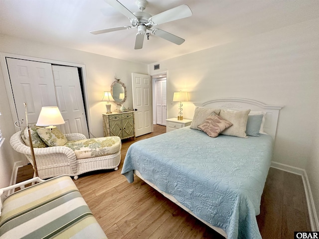 bedroom with a closet, visible vents, ceiling fan, wood finished floors, and baseboards