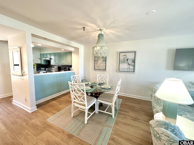 dining room featuring a notable chandelier, wood finished floors, and baseboards