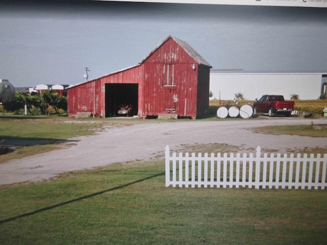 view of barn featuring fence and a yard