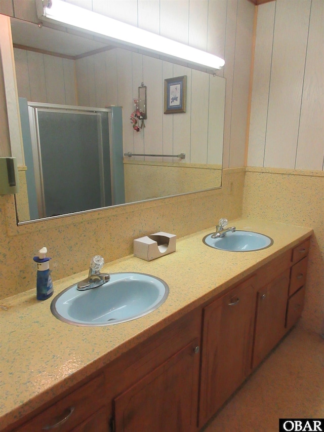 full bathroom with double vanity, a stall shower, and a sink