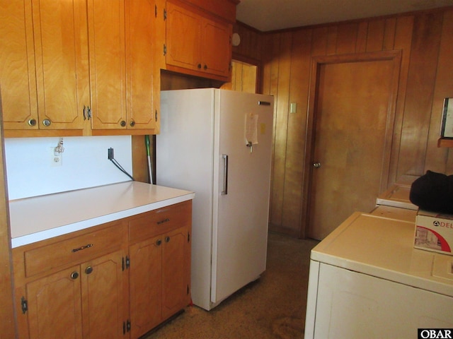 kitchen featuring brown cabinets, freestanding refrigerator, washing machine and dryer, and light countertops