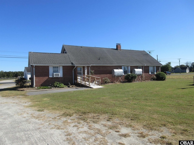 view of front of home with roof with shingles, brick siding, a chimney, and a front yard