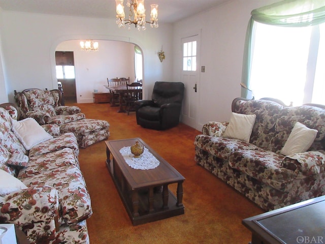 carpeted living room with arched walkways and a chandelier