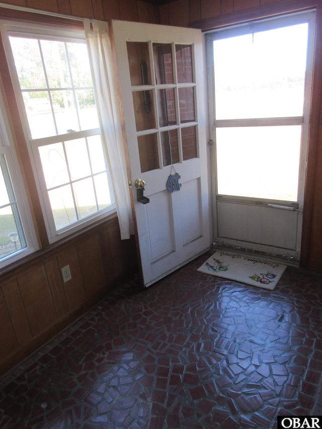 entryway with stone finish floor and wooden walls