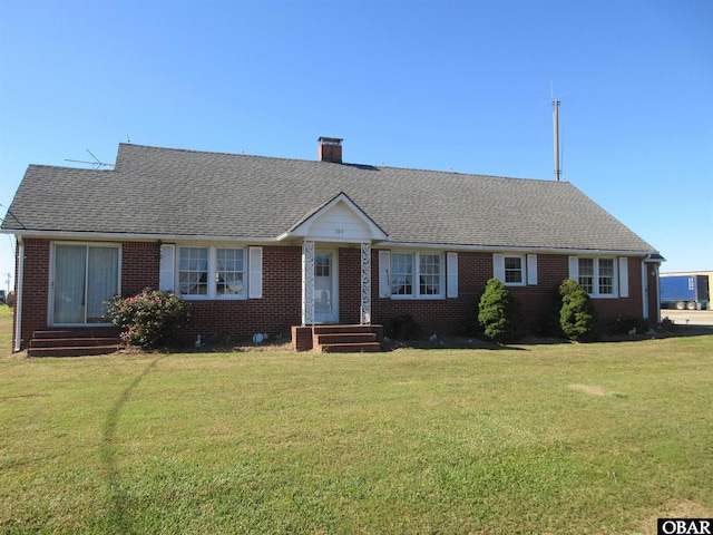 ranch-style home featuring entry steps, brick siding, a front lawn, and roof with shingles