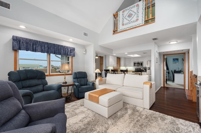 living area with high vaulted ceiling, dark wood-style flooring, and visible vents