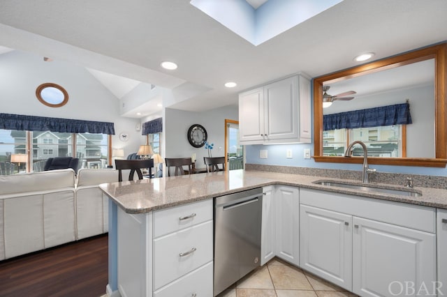 kitchen with open floor plan, white cabinets, a sink, dishwasher, and a peninsula