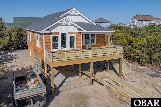 view of front facade featuring roof with shingles, board and batten siding, and a wooden deck