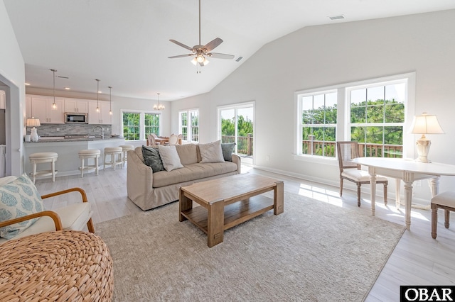 living room with lofted ceiling, plenty of natural light, visible vents, and light wood-style flooring