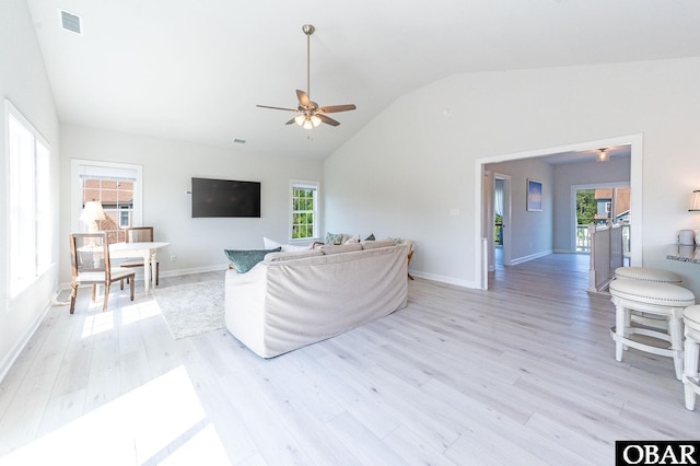 living room with lofted ceiling, light wood finished floors, visible vents, and a healthy amount of sunlight