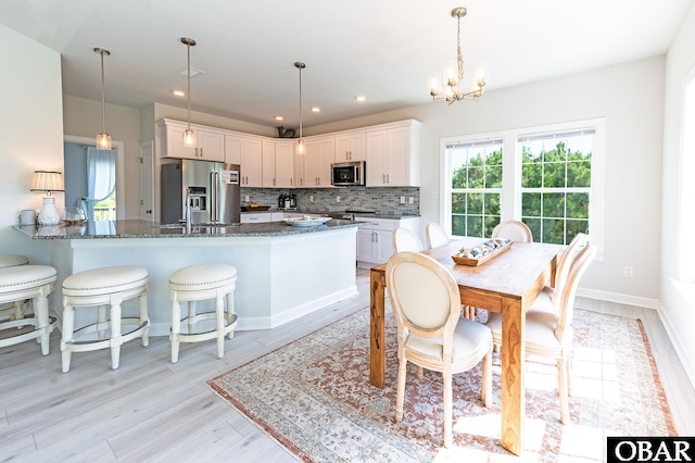 dining room featuring light wood-style floors, baseboards, a chandelier, and recessed lighting