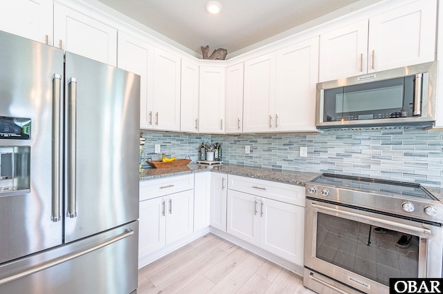 kitchen with stainless steel appliances, light stone countertops, white cabinets, and tasteful backsplash