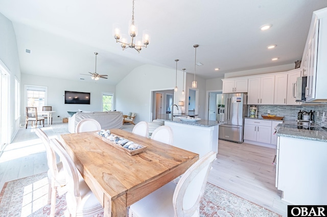 dining space with light wood-style floors, recessed lighting, vaulted ceiling, and ceiling fan with notable chandelier