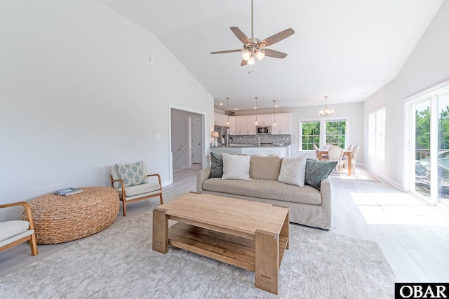 living area with light wood finished floors, baseboards, and high vaulted ceiling