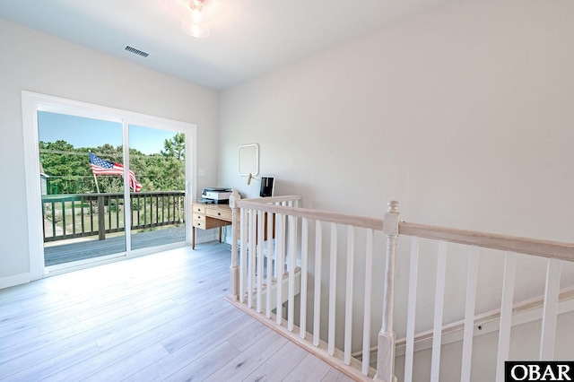 hall featuring light wood finished floors, an upstairs landing, and visible vents