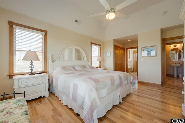 bedroom featuring lofted ceiling, light wood-type flooring, baseboards, connected bathroom, and visible vents