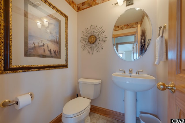 bathroom featuring toilet, a sink, and baseboards
