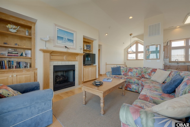 living area featuring light wood-type flooring, a wealth of natural light, vaulted ceiling, and visible vents
