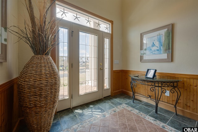 foyer featuring plenty of natural light, wainscoting, and wooden walls