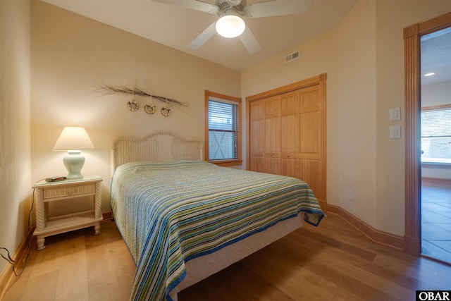 bedroom with a closet, baseboards, visible vents, and wood finished floors