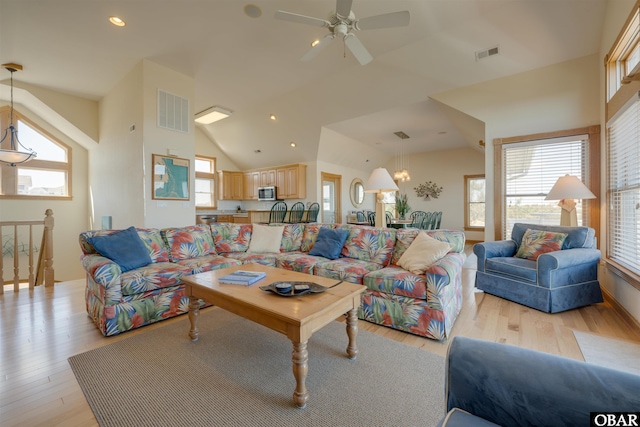 living area with visible vents, vaulted ceiling, and light wood-type flooring