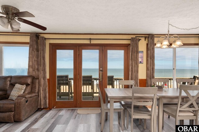 dining area with a water view, a textured ceiling, and wood finished floors