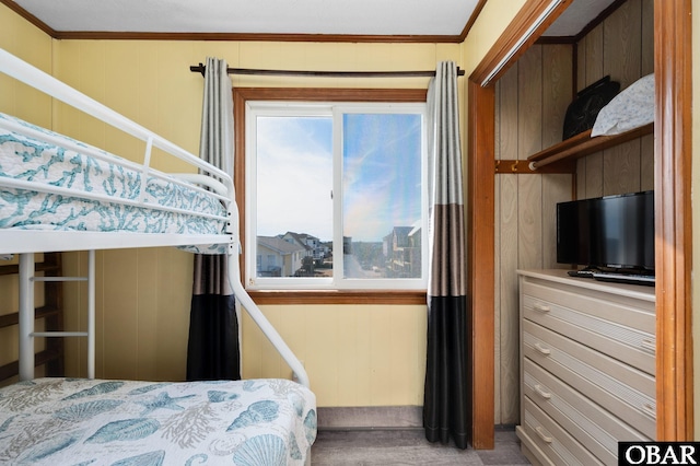 carpeted bedroom featuring wooden walls and crown molding