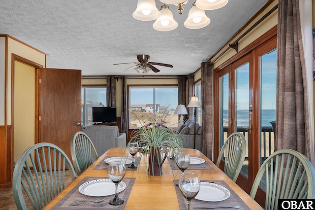 dining area featuring a textured ceiling and ceiling fan with notable chandelier