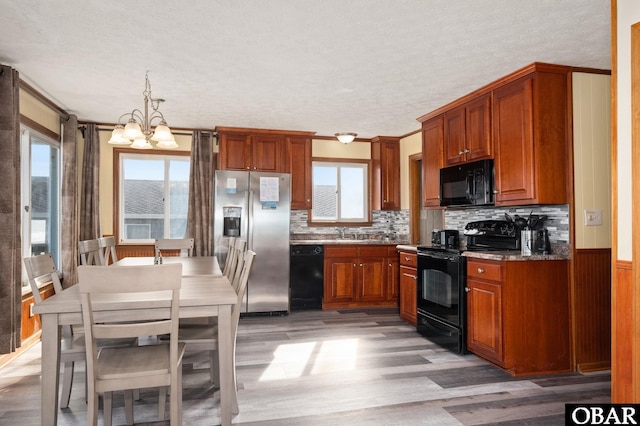 kitchen featuring black appliances, a notable chandelier, light wood-style floors, and a wealth of natural light